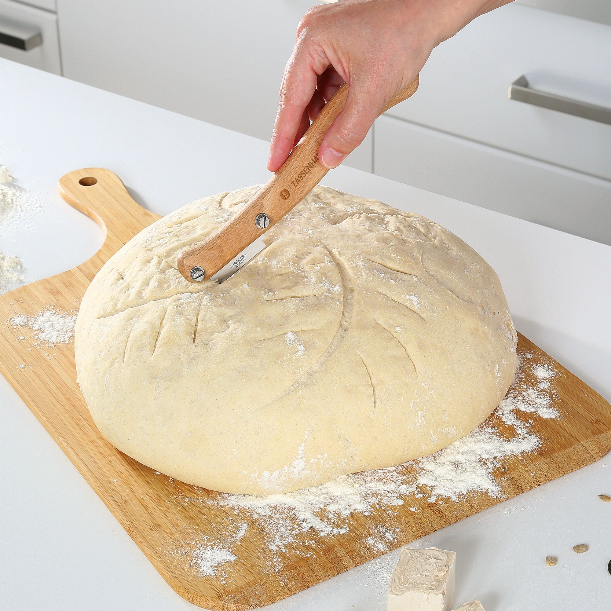 Hand schneidet Brotlaib mit Zassenhaus Bäckermesser aus Buch